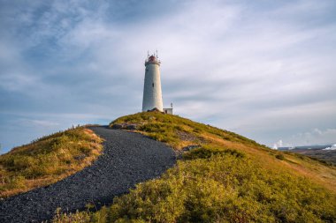 Reykjanesviti Lighthouse emerges from the thick geothermal steam of Gunnuhver a striking scene in Icelands southwest clipart