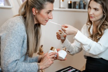 Consultation with two women about aromatherapy and cosmetic treatment in a beauty salon clipart