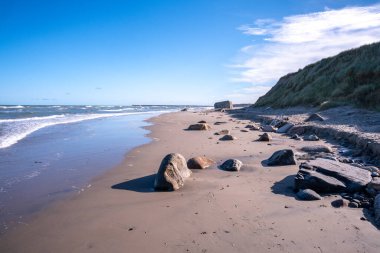 Yaz güneşi Kuzey Denizi 'nin üzerinde parlayarak Hirtshals, Jutland' daki kumlu sahilde barışçıl bir atmosfer yaratır.