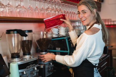 Kahve makinesiyle kahve hazırlayan profesyonel sarışın barista. Genç bayan kahve yapıyor.