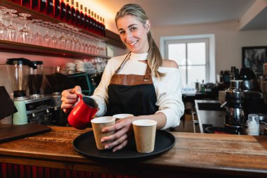 Kahve barında kahve hazırlayan sarışın. Kağıt bardakta kahve hazırlıyor.