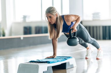 Sarışın, atletik bir kadın spor salonunda çalışıyor.