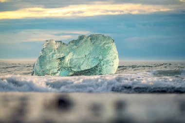 Güneşin doğuşuyla birlikte Jkulsrln yakınlarındaki buzul plajındaki eriyen buzuldan bir buz kütlesinin yakınına İzlanda 'daki Vatnajkull Ulusal Parkı' na.