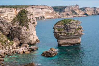 Korsika 'nın güneyindeki Bonifacio kıyısındaki gezinti güvertesinden mavi denize bakan beyaz tebeşir kayalıkları.