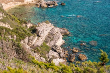 Korsika 'nın güneyindeki Bonifacio kıyısındaki gezinti güvertesinden mavi denize bakan beyaz tebeşir kayalıkları.