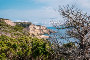 Korsika 'nın güneyindeki Bonifacio kıyısındaki gezinti güvertesinden mavi denize bakan beyaz tebeşir kayalıkları.