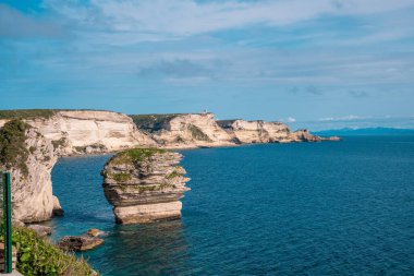 Korsika 'nın güneyindeki Bonifacio kıyısındaki gezinti güvertesinden mavi denize bakan beyaz tebeşir kayalıkları.