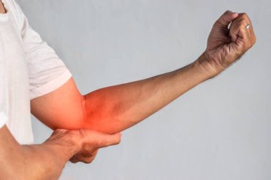 Güneydoğu Asyalı genç adamın dirsek ekleminde ağrı var. Dirsek ağrısı, yaralanma, romatizma veya osteoartrit kavramı.