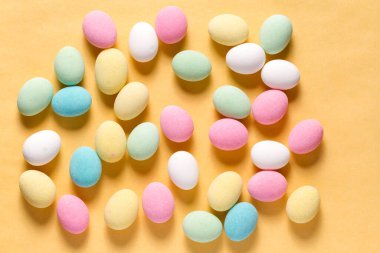 Pile of sweets on yellow background, top view