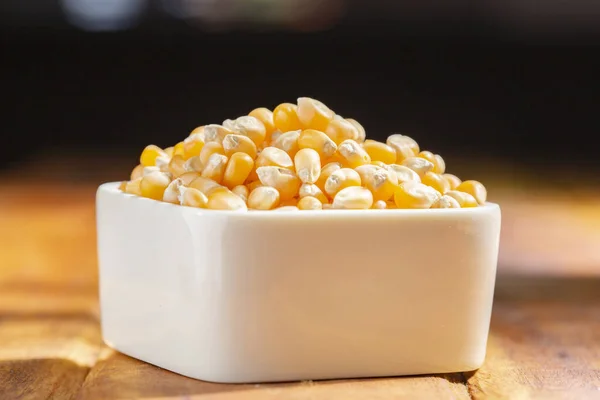 stock image Popcorn kernels in bowl on wooden surface