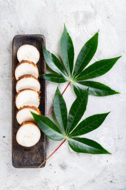 Beyaz bir zemin üzerinde ahşap tepsiler üzerinde kasava dilimleri (Manihot esculenta)