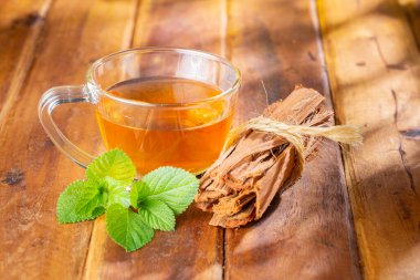 Cam fincanda kedi pençesi çayı, ahşap yüzeyde, kraliyet ailesi yok.