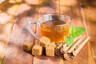 Cane panela çayı ve tarçın cipsi, cam bir fincanda, ahşap bir yüzeyde, kraliyet ailesi olmadan.