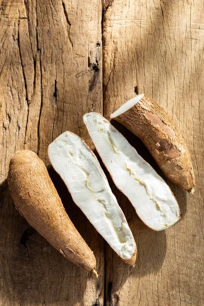 stock image cassava pile, yucca, on a background of rustic wood (Manihot esculenta)