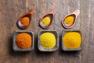 Ahşap arka planda zerdeçal, biber ve köri tozu.