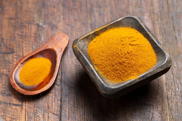 Ahşap arka planda zerdeçal, biber ve köri tozu.