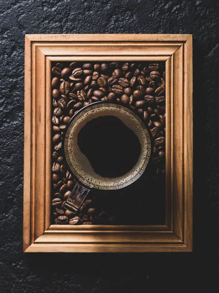 stock image cup of coffee with roasted coffee beans, on a wooden frame, top view