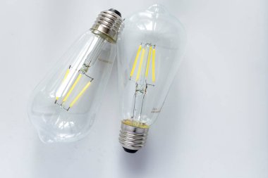 Beyaz arka planda görünen filateli olan iki cam LED ampul bulunuyor. Ampuller standart vida tabanına sahiptir ve bu yüzden bir ampulün tabanı çerçevenin en üstünde diğerinin tabanı ise en alttadır..