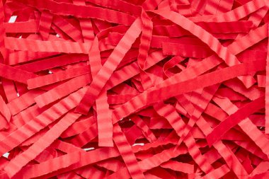 A closeup image of red shredded paper filling the entire frame, creating a textured backdrop. The paper is torn into long, thin strips, showcasing a vibrant red hue. clipart