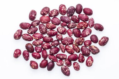 Beyaz arka plana saçılmış kırmızı ve beyaz fasulyelerin yakın plan çekimi. Fasulyelerin kırmızı ve beyaz renkli benekli bir görünüşü var..