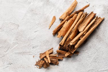 Beyaz desenli arka planda düzenlenmiş kırık tarçın çubukları ve parçaları..