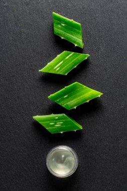 Ale Vera yaprakları ve aloe özü bir kabın içinde, arka planda, yukarıdan görülür.