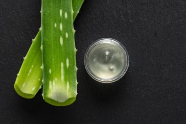 Ale Vera yaprakları ve aloe özü bir kabın içinde, arka planda, yukarıdan görülür.