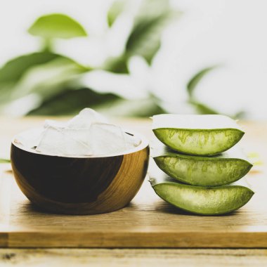 Resimde Aloe Vera bitkisi yaprakları görülüyor, bir kesme tahtasının üzerinde posası.