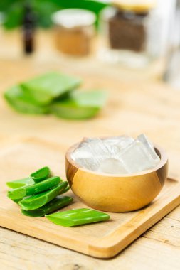 Resimde Aloe Vera bitkisi yaprakları görülüyor, bir kesme tahtasının üzerinde posası.