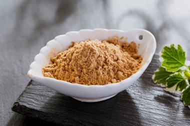 Tahta bir kapta gri bir yüzey üzerinde tıbbi maca tozu.