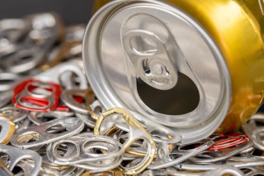 Bir sürü alüminyum kutu halkası ve bira kutusu görülür, yakın plan görüntü.