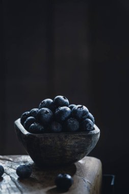 Yaban mersini yığını ahşap kabın içinde, koyu bir arka planda, yakın plan.