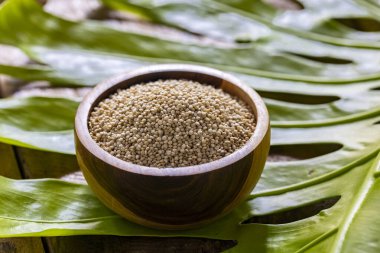 Resimde bir yığın quinua taneciği görülüyor, ahşap bir kabın içinde.