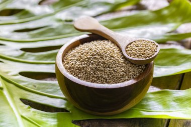 Resimde bir yığın quinua taneciği görülüyor, ahşap bir kabın içinde.