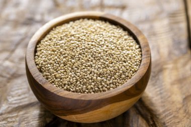 Resimde bir yığın quinua taneciği görülüyor, ahşap bir kabın içinde.