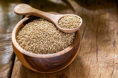 Resimde bir yığın quinua taneciği görülüyor, ahşap bir kabın içinde.