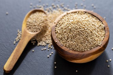 Resimde bir yığın quinua taneciği görülüyor, ahşap bir kabın içinde.