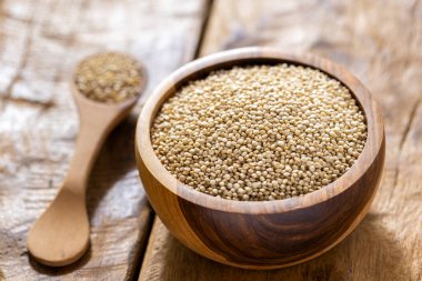 Resimde bir yığın quinua taneciği görülüyor, ahşap bir kabın içinde.