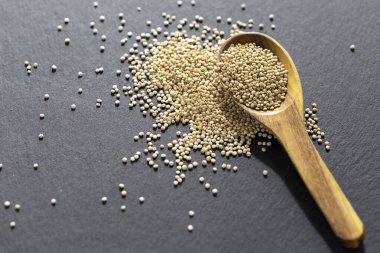 Resimde bir yığın quinua taneciği görülüyor, ahşap bir kabın içinde.