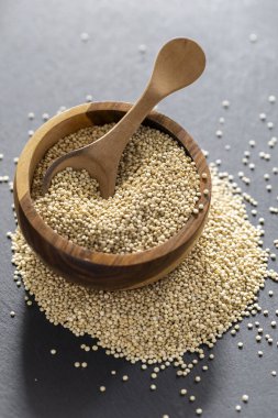 Resimde bir yığın quinua taneciği görülüyor, ahşap bir kabın içinde.