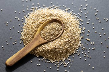 Resimde bir yığın quinua taneciği görülüyor, ahşap bir kabın içinde.