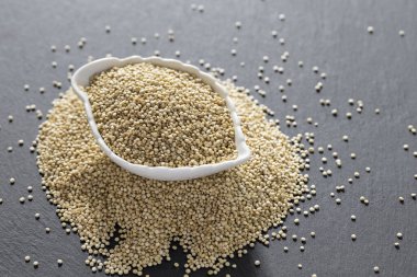 Resimde seramik bir kapta kinoa tanecikleri yığını görülüyor.