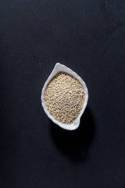 Resimde seramik bir kapta kinoa tanecikleri yığını görülüyor.