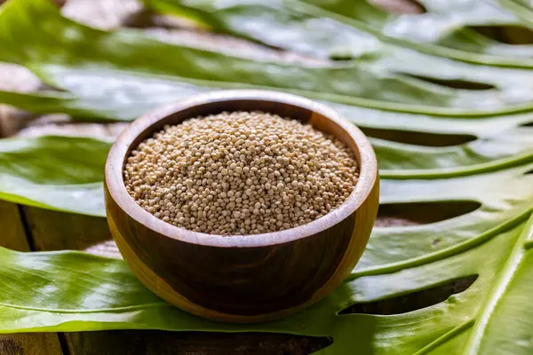 Resimde bir yığın quinua taneciği görülüyor, ahşap bir kabın içinde.