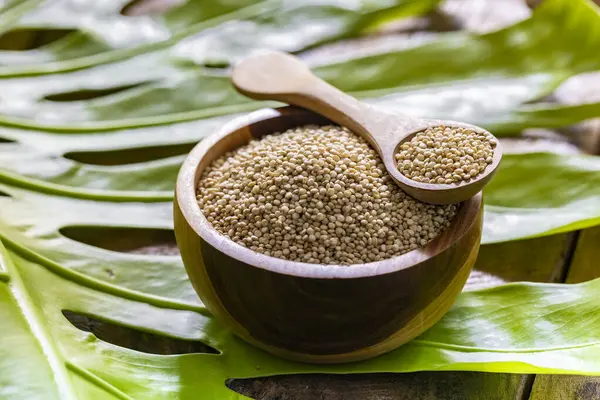 Resimde bir yığın quinua taneciği görülüyor, ahşap bir kabın içinde.