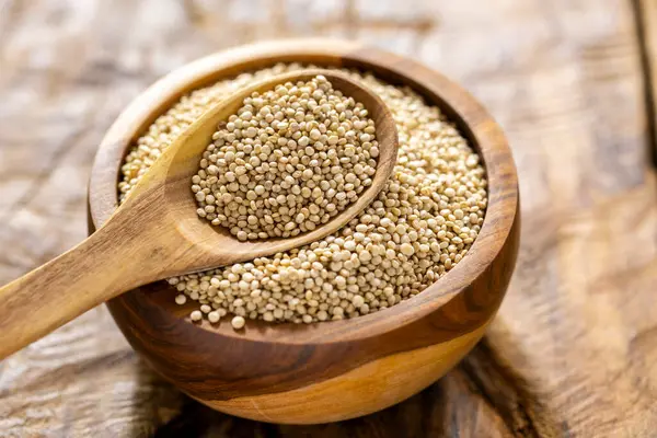 Resimde bir yığın quinua taneciği görülüyor, ahşap bir kabın içinde.