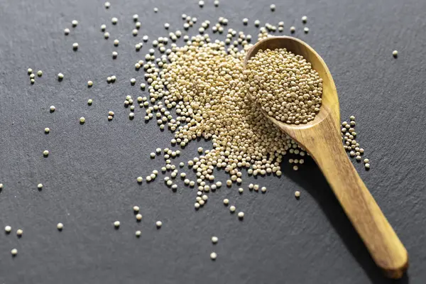 Resimde bir yığın quinua taneciği görülüyor, ahşap bir kabın içinde.