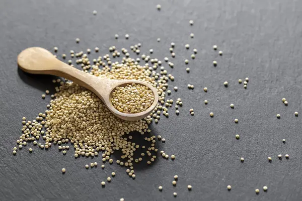 Resimde bir yığın quinua taneciği görülüyor, ahşap bir kabın içinde.