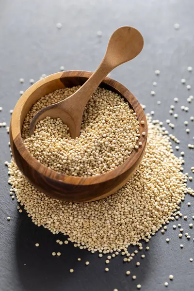 Resimde bir yığın quinua taneciği görülüyor, ahşap bir kabın içinde.