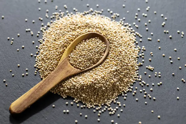 Resimde bir yığın quinua taneciği görülüyor, ahşap bir kabın içinde.